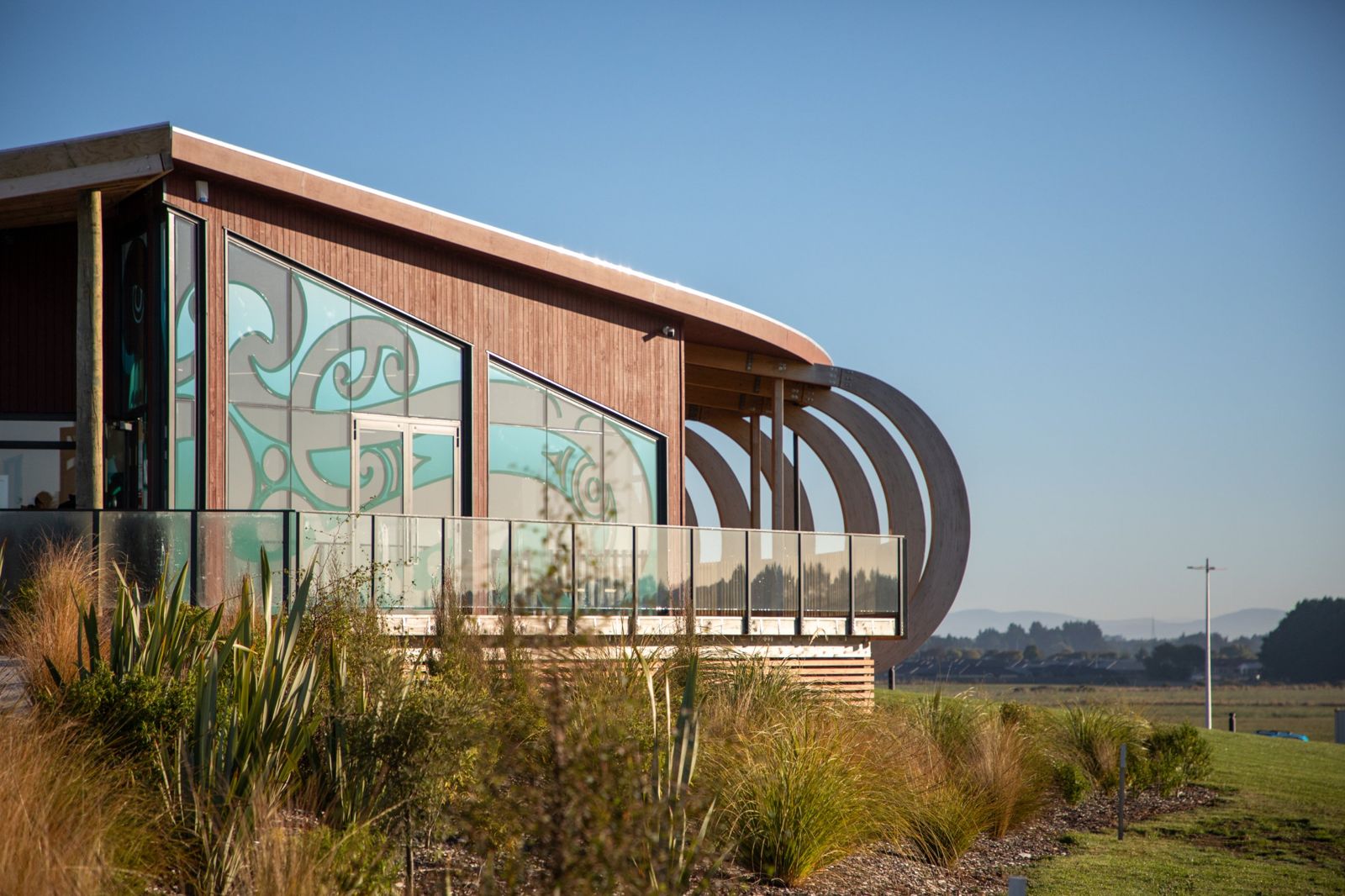 Teal patterned glass of the marae with native plantings